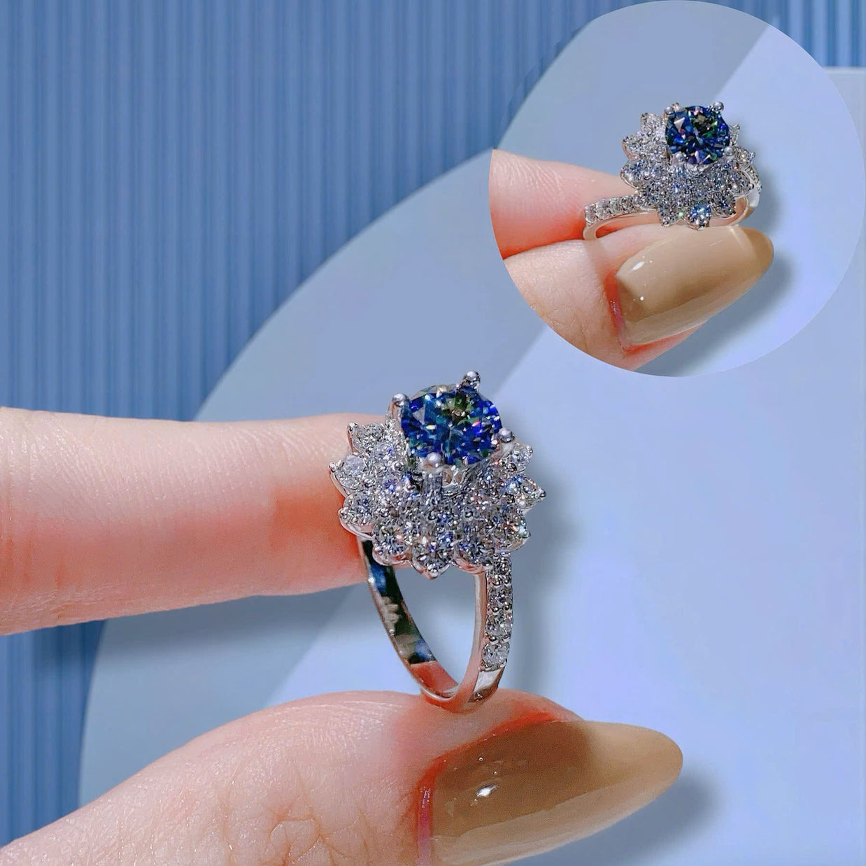 Silver ring with blue gemstone on a finger against a light blue background