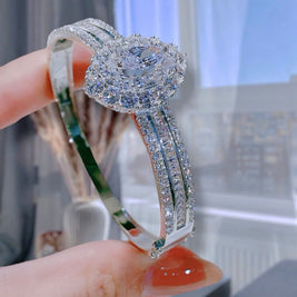 Silver ring with gemstones held by a hand against a blurred indoor background