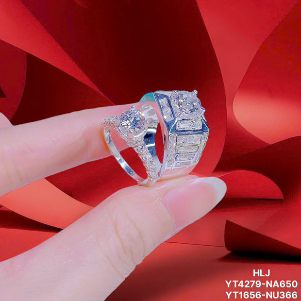 Silver ring with gemstones held by a hand against a red fabric background
