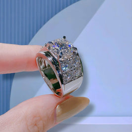 Silver ring with gemstones on a finger against a light blue background