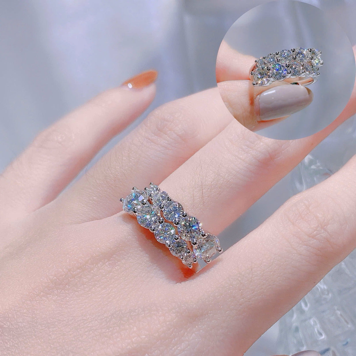 Silver ring with gemstones on a hand against a neutral background