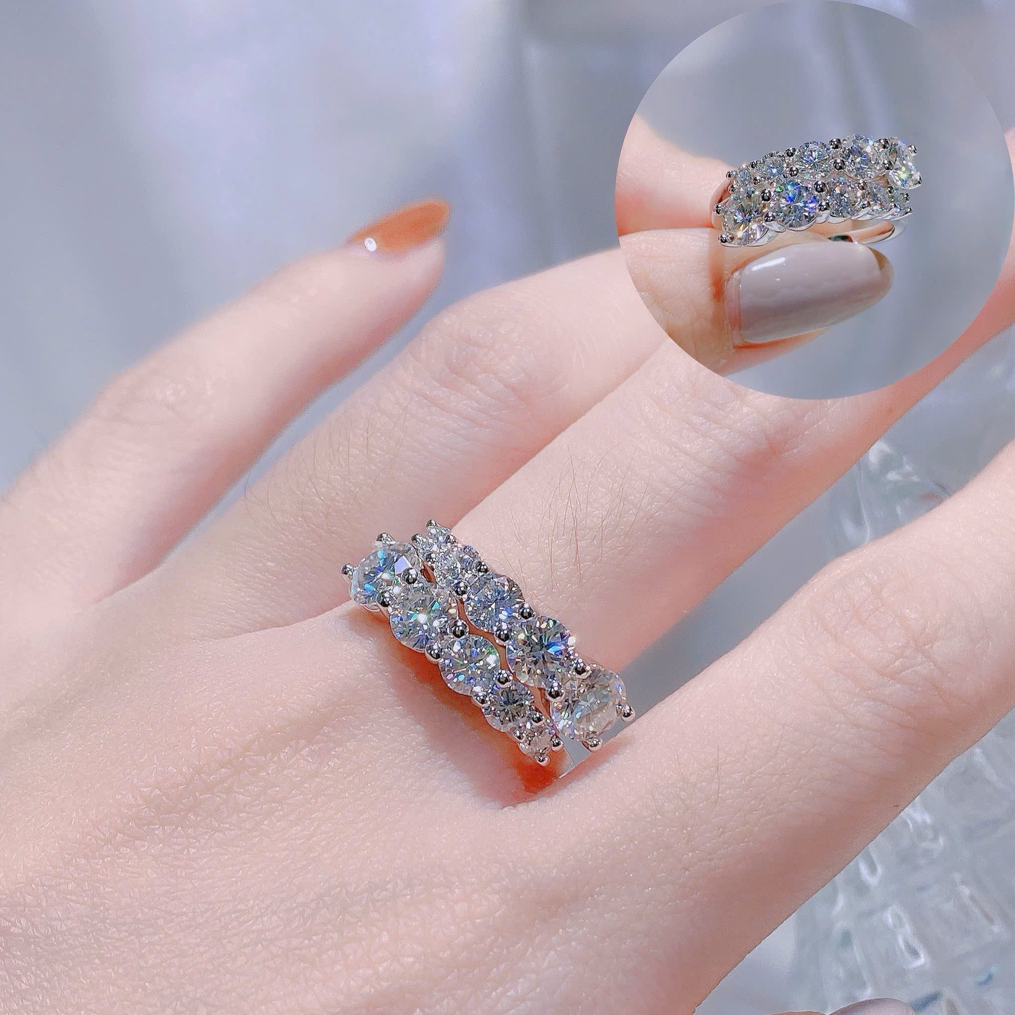 Silver ring with gemstones on a hand against a neutral background