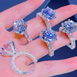 Silver ring with large gemstones held in a hand against a dark background