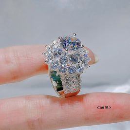 Silver ring with multiple gemstones on a finger against a neutral background