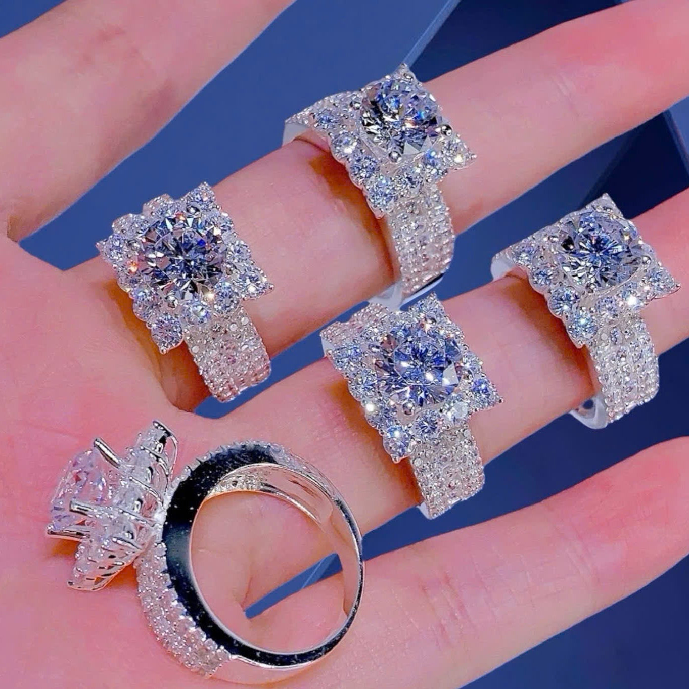 Silver rings with gemstones on a hand against a blue background