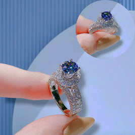Silver rings with blue gemstones held by a hand against a light background