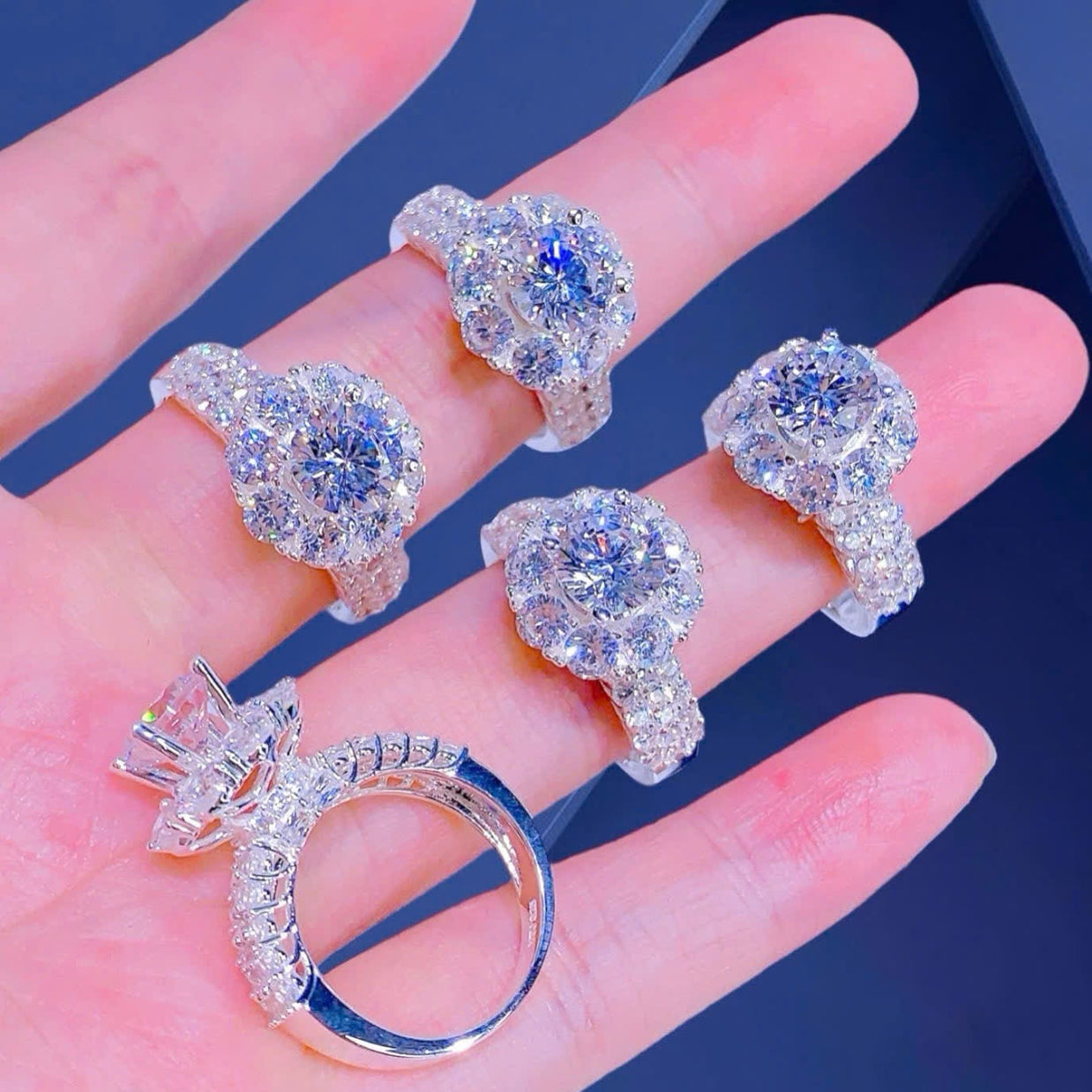 Silver rings with gemstones on a hand against a dark background