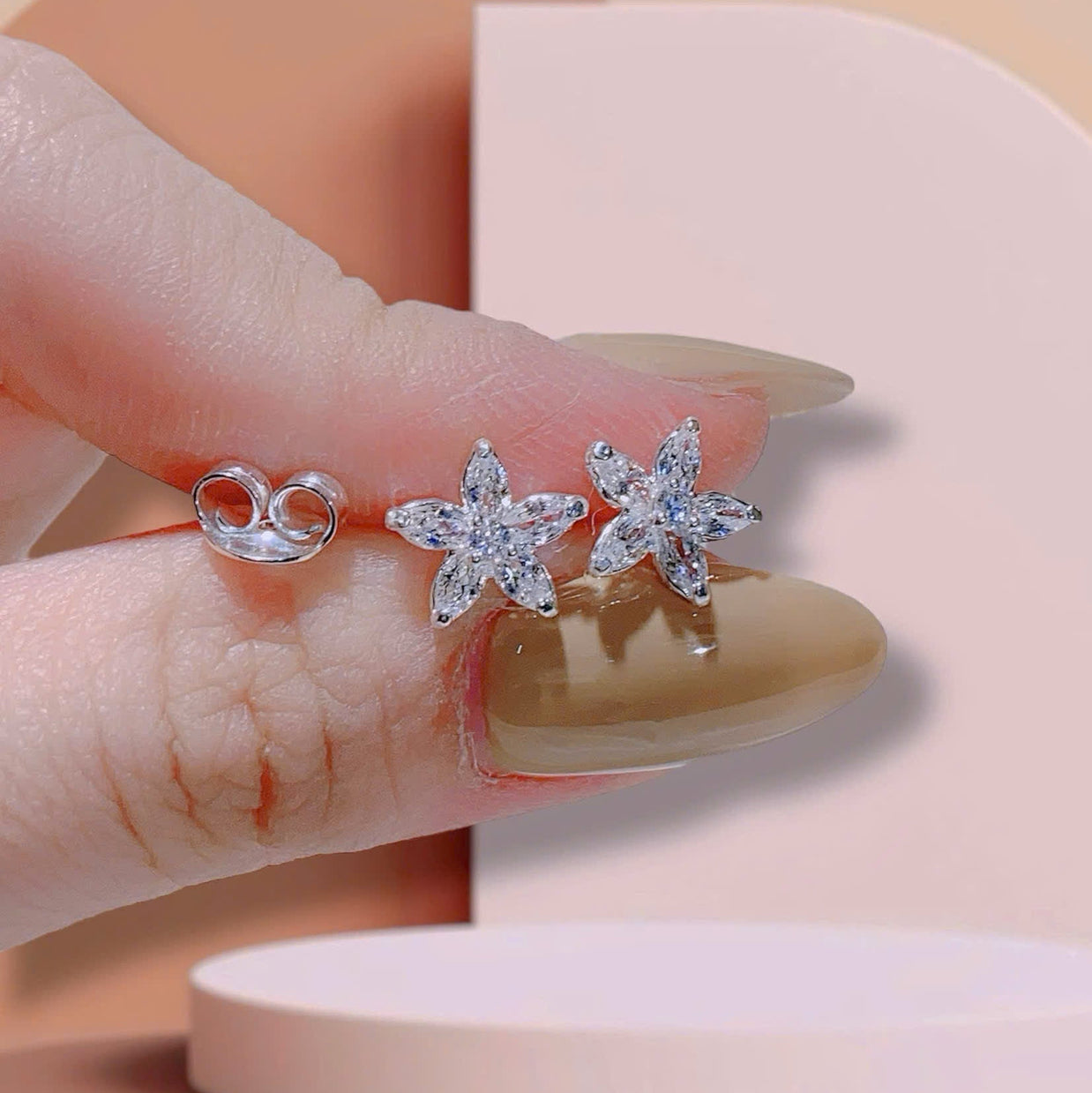 Star-shaped earrings held between fingers with a soft background