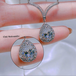 Teardrop-shaped diamond pendant on a hand with close-up detail