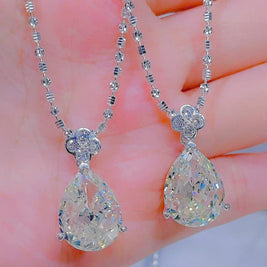 Teardrop-shaped diamond pendants on a chain held in hand