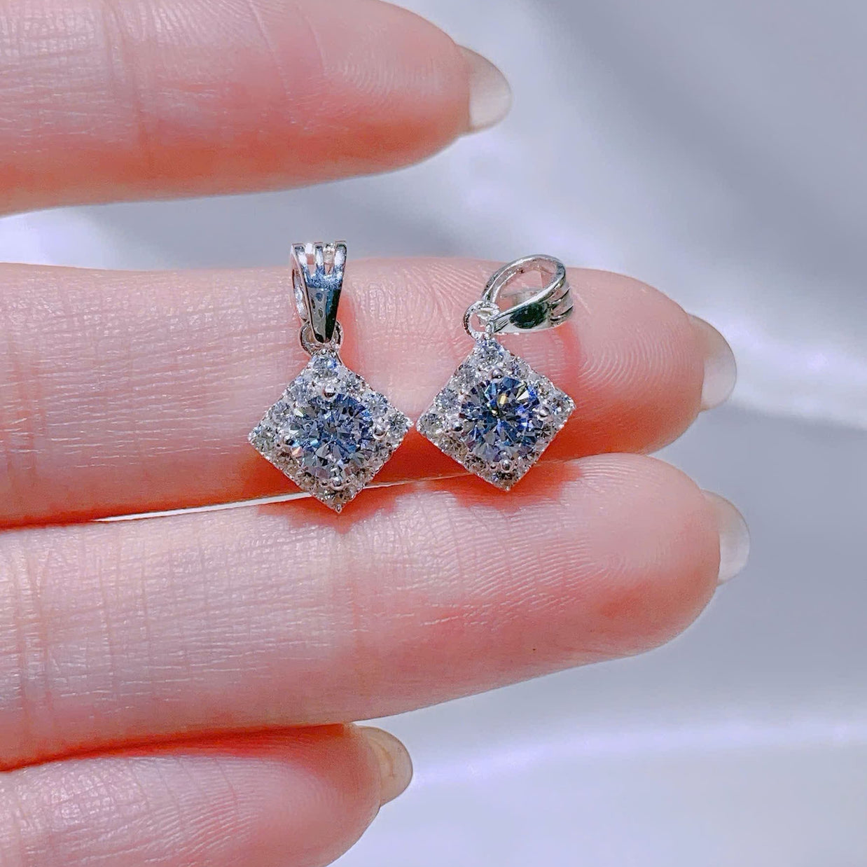 Silver earrings with blue gemstones held between fingers against a neutral background