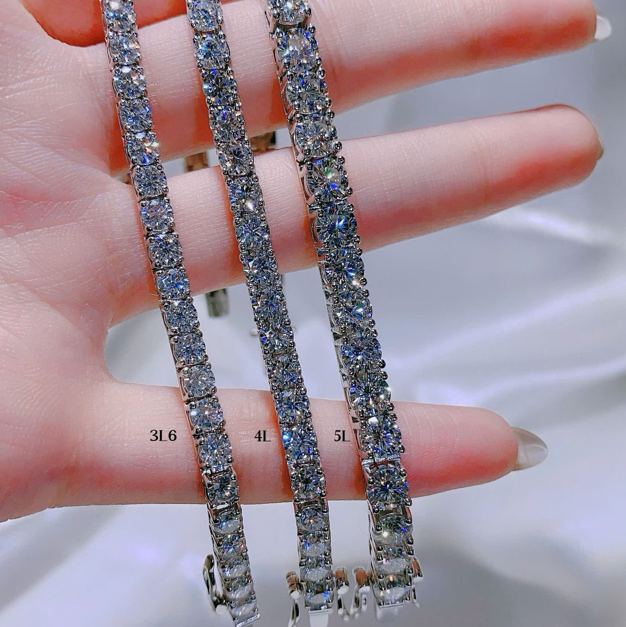 Three diamond tennis bracelets on a hand with a blurred background