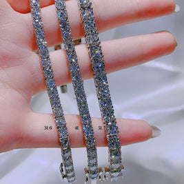 Three diamond tennis bracelets on a hand with a blurred background