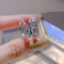 Three silver rings with gemstones on a finger against a neutral background