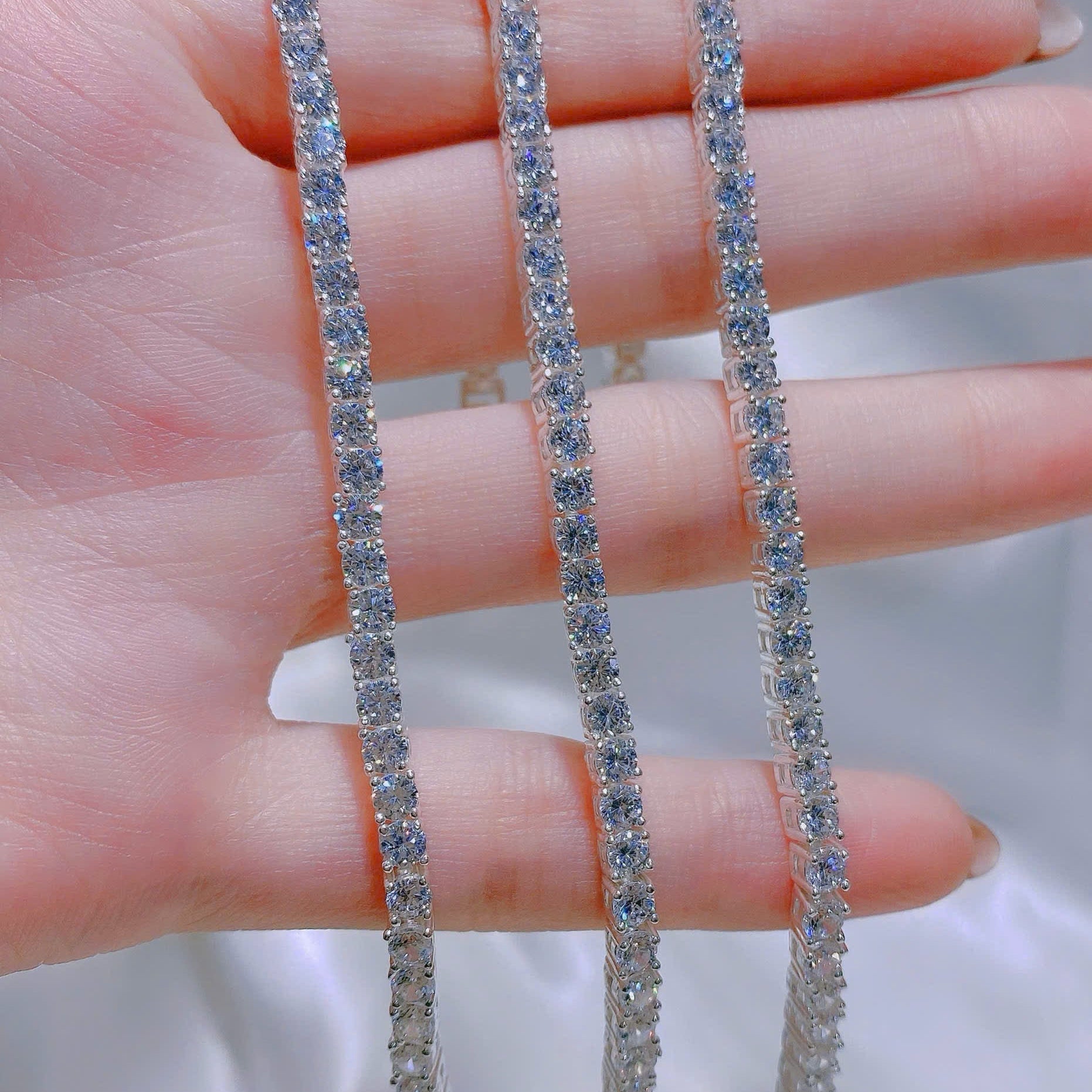 Two diamond bracelets on a hand with a blurred background