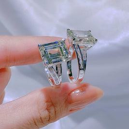 Two diamond rings held between fingers against a neutral background