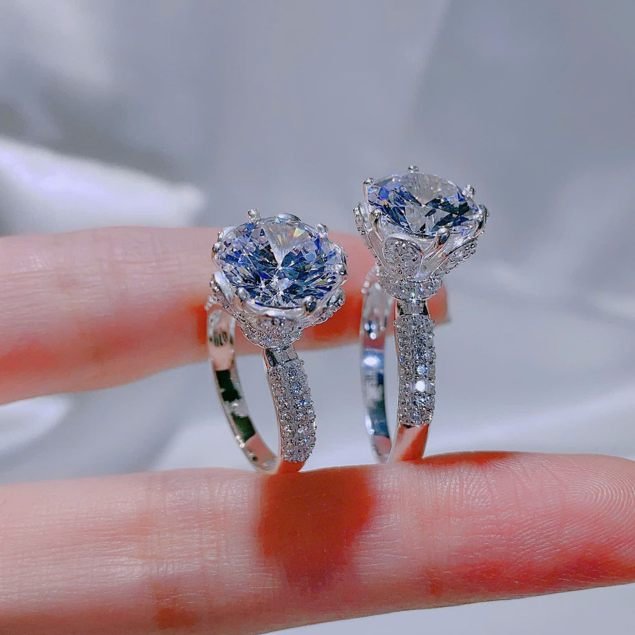Two diamond rings held on a finger with a blurred background