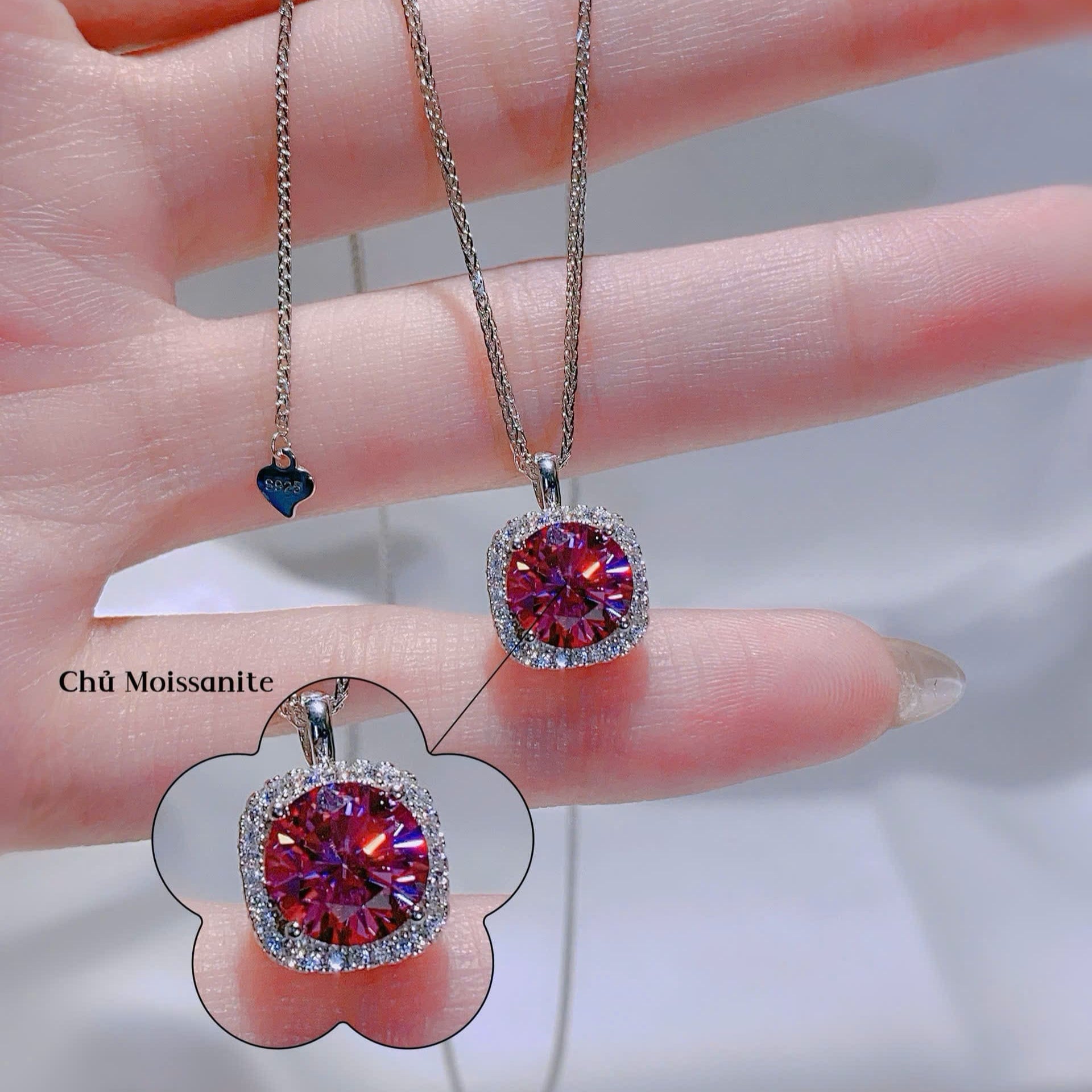 Two gemstone pendants on a hand with a blurred background