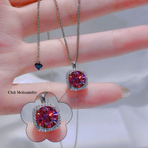 Two gemstone pendants on a hand with a blurred background