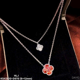 Two silver necklaces with floral pendants on a black stand.