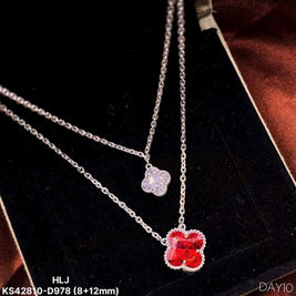Two silver necklaces with red and clear pendants on a dark surface.
