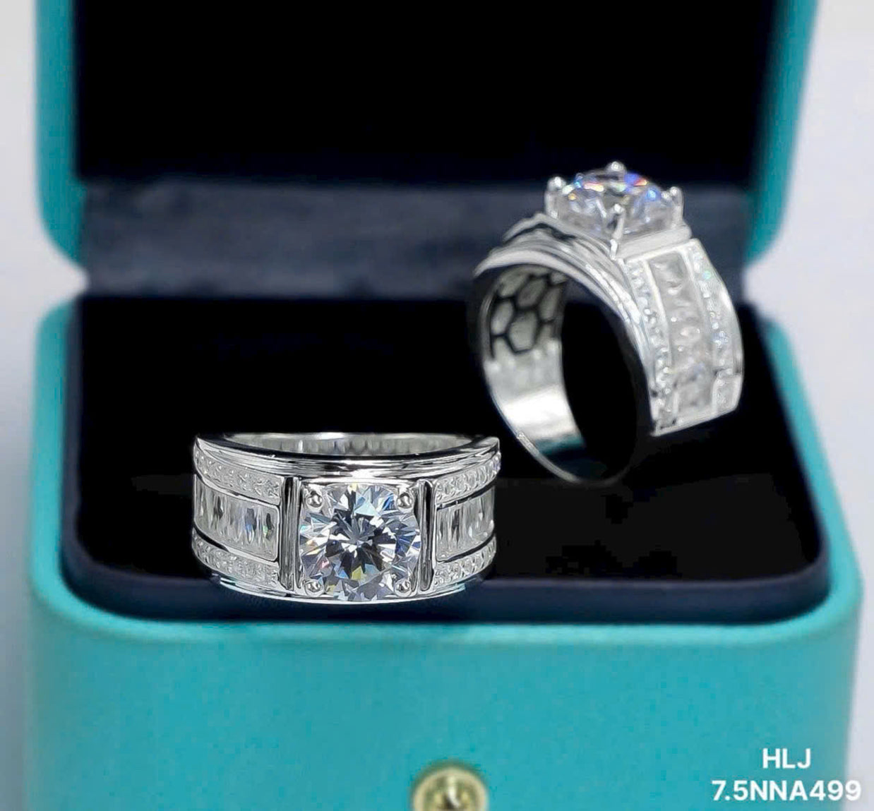 Two silver rings with gemstones in a teal box.