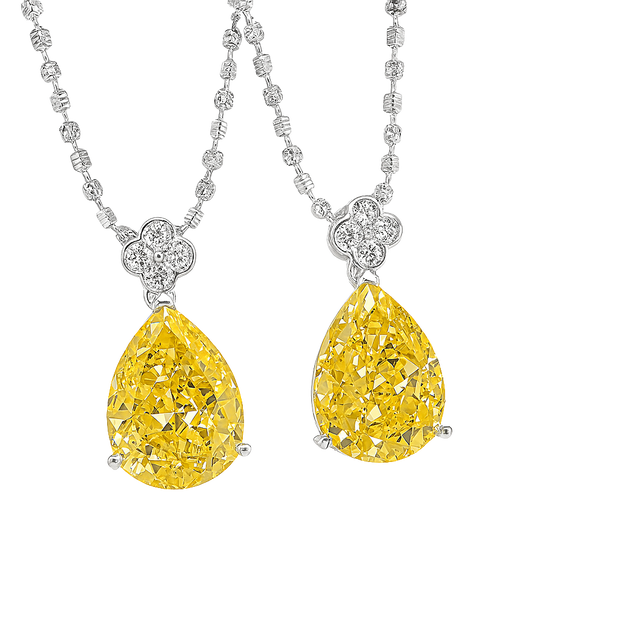 Two yellow diamond pendants on a silver chain against a white background